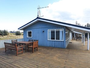 A blue building with a covered deck, a table with chairs, and a satellite dish.