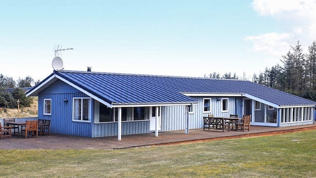 Un bâtiment bleu avec un toit en pente, un patio couvert et une terrasse.