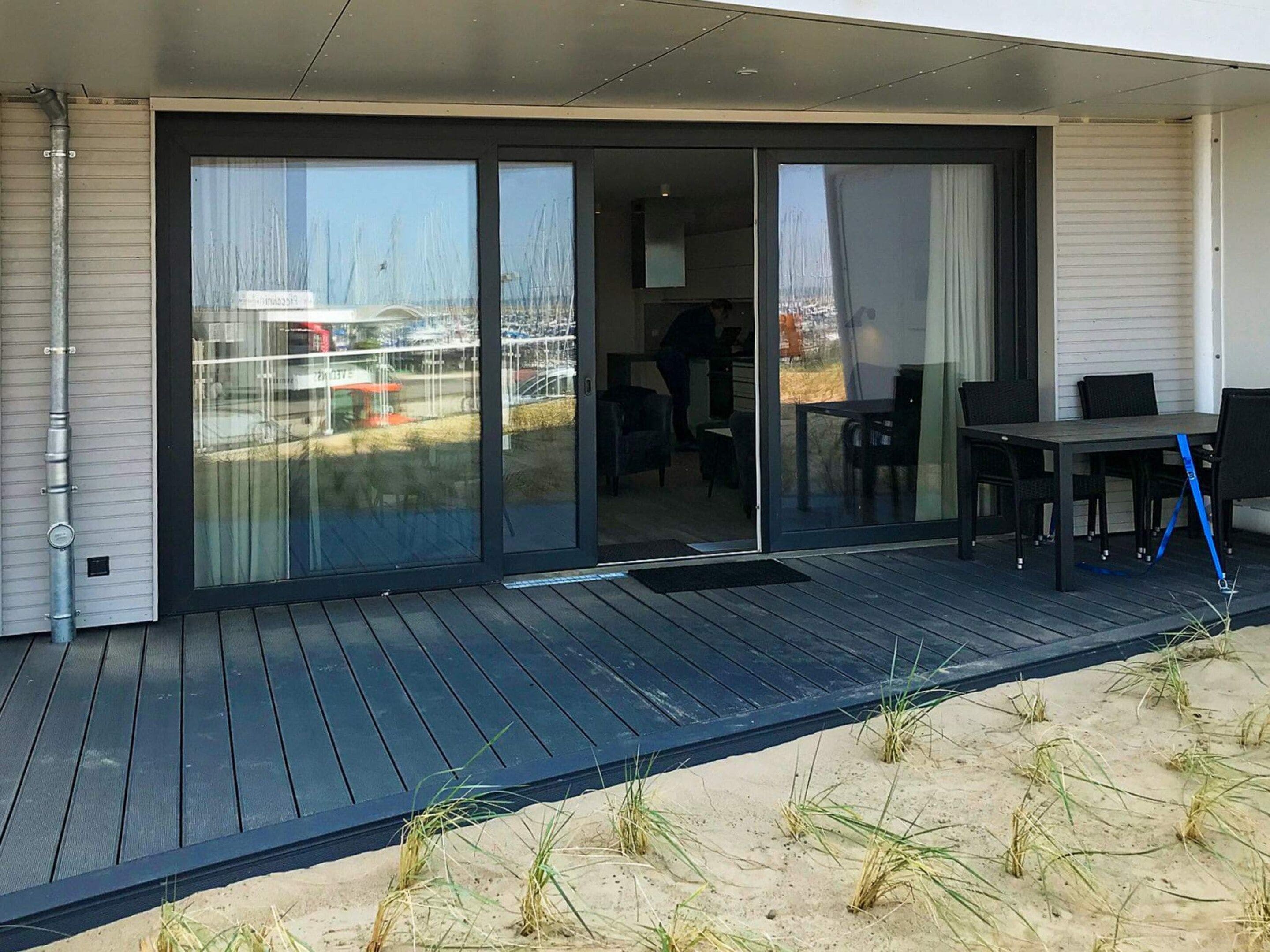 A modern outdoor deck with a sliding glass door leading to a patio area.