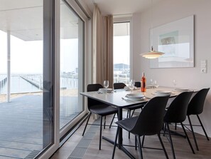 A dining area with a table set for four, large windows, and a view of a pier. - 5 Star Holiday Home in Wendtorf (Wendtorf)