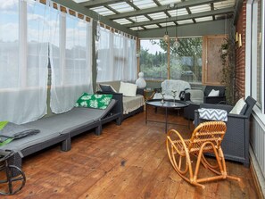 A covered outdoor seating area with wicker furniture, a table, and a swing chair. - 8 Person Holiday Home in Hvide Sande (Hvide Sande)