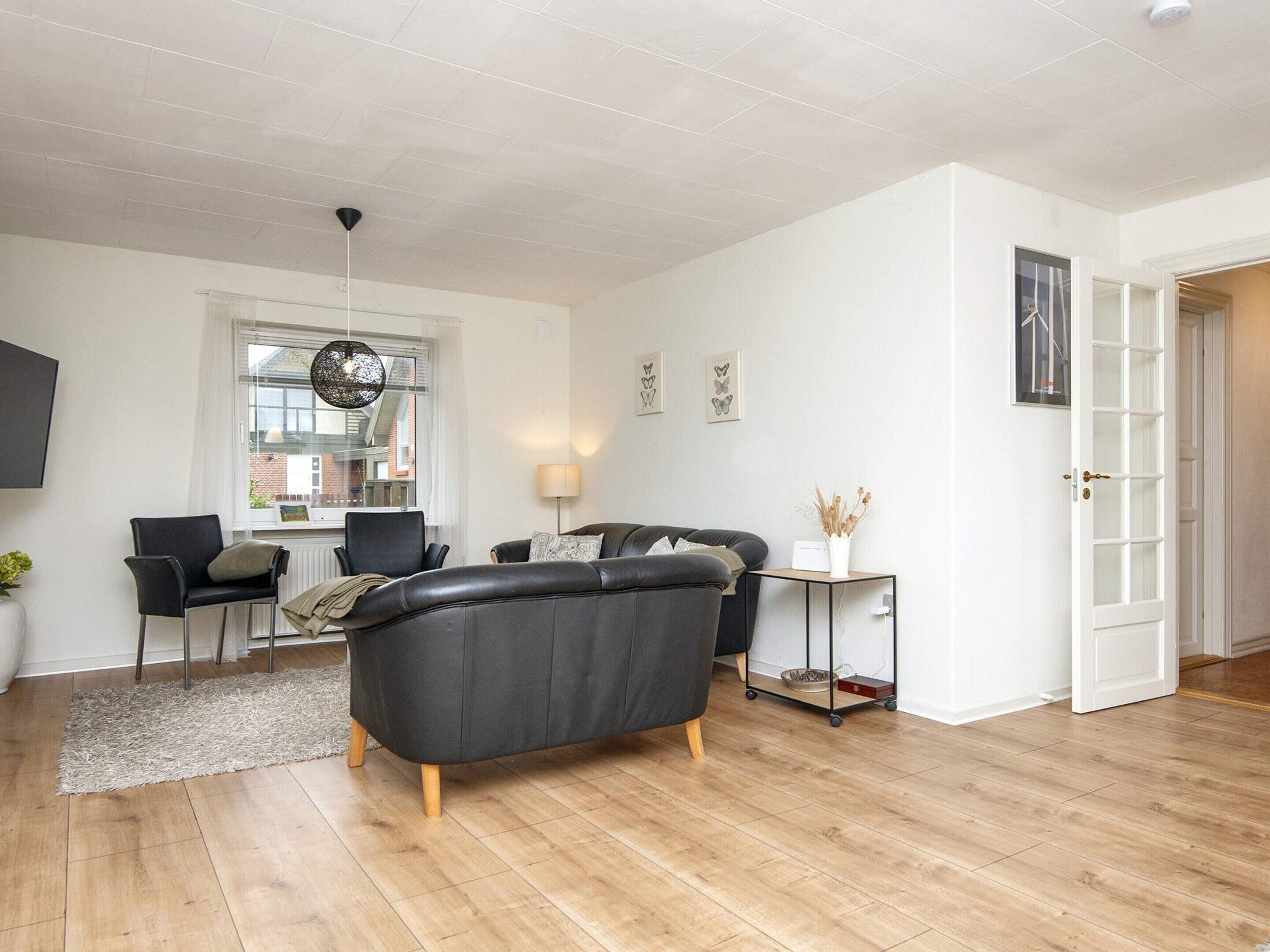 A modern living room with a sofa, chairs, a coffee table, and a lamp.