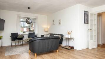 A modern living room with a sofa, chairs, a coffee table, and a lamp.