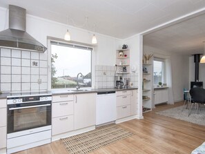 A modern kitchen with white cabinetry, a built-in oven, a large window, and a view of the outdoors.