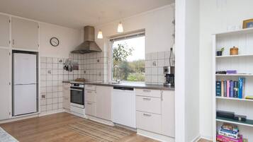 A modern kitchen with white cabinetry, a built-in oven, a coffee maker, and a window with a view of greenery.
