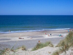 A beach with people sunbathing and swimming, and a clear blue sky. - 8 Person Holiday Home in Hvide Sande (Hvide Sande)