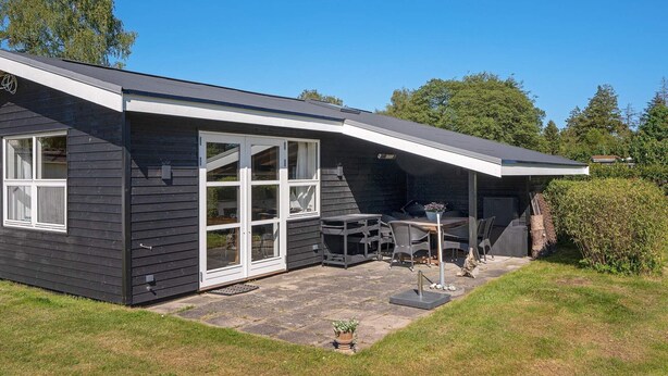 A modern house with a covered patio, a dining area, and a garage. - 4 Person Holiday Home in Vaeggerlose (Vaeggerlose)