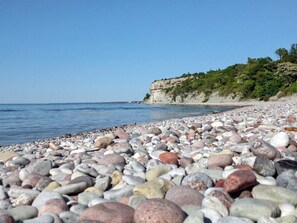 A pebble beach with a rocky shoreline and a cliff in the background. - 4 Person Holiday Home in Visby (Visby)