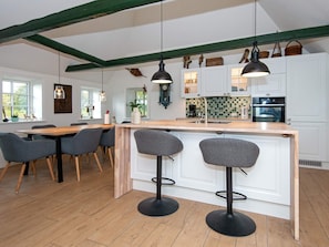A modern kitchen with white cabinets, a wooden island with bar stools, and pendant lighting. - 6 Person Holiday Home in Varde (Varde)