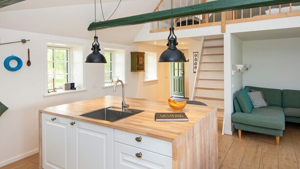 A modern kitchen with a wooden island, white cabinets, and a book titled "GASTEBOG" on the counter. - 6 Person Holiday Home in Varde (Varde)