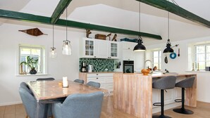 A modern kitchen with white cabinets, a green tiled backsplash, and a wooden island with bar stools. - 6 Person Holiday Home in Varde (Varde)