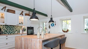 A modern kitchen with white cabinets, a wooden island, two bar stools, and pendant lighting. - 6 Person Holiday Home in Varde (Varde)