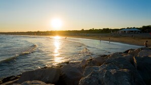 A beach scene with rocks in the foreground, a clear sky, and a sunset. - Mobile home in Cesenatico, 2 bedrooms 2 bathrooms on the camping close to nature (Cesenatico)