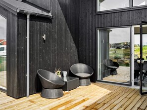 A modern outdoor seating area with wicker furniture and a wooden deck.
