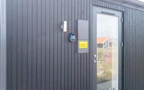 A gray building with a door, a small window, and a sign on the wall.