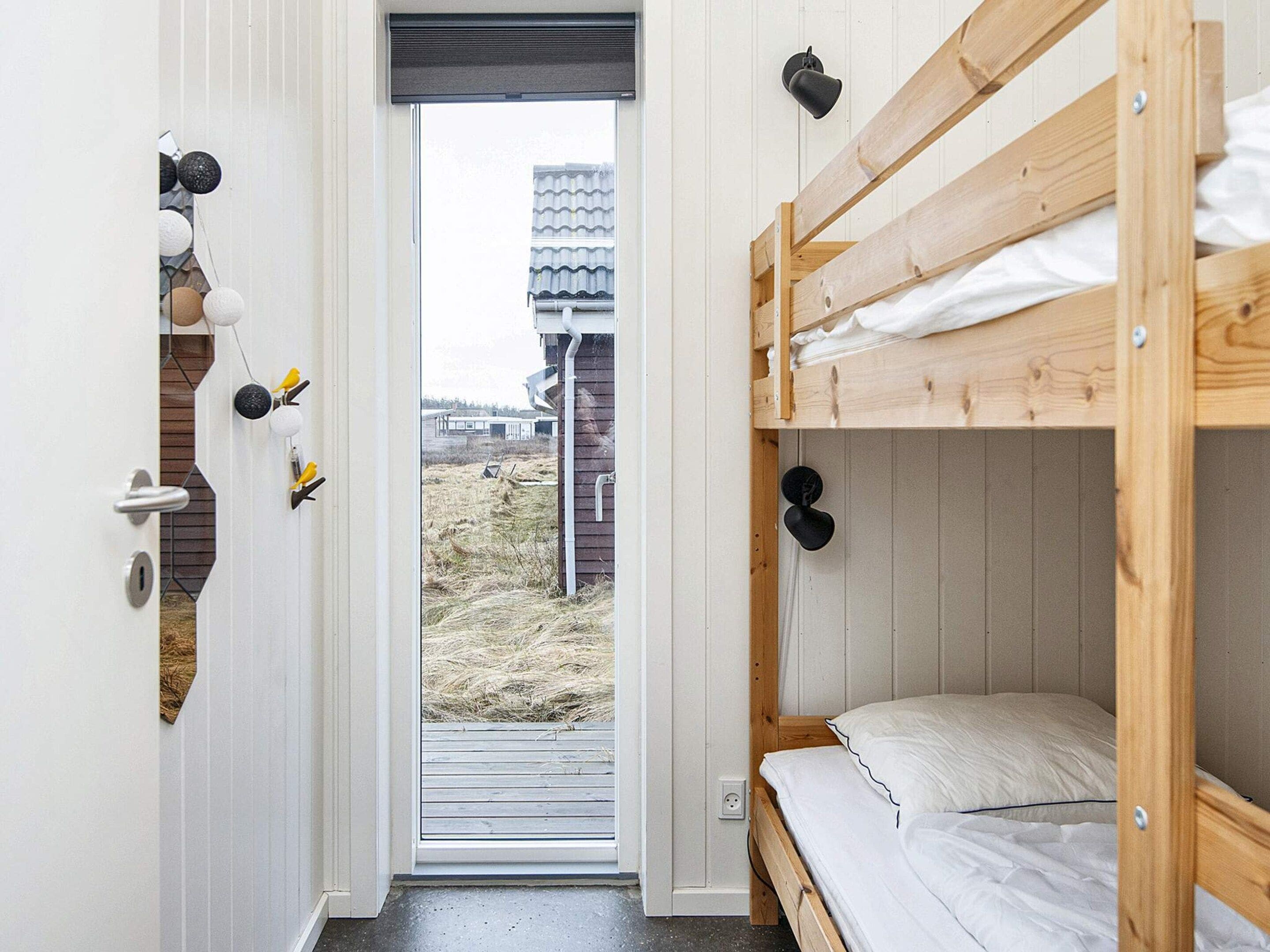A room with a bunk bed, a door with a view to the outside, and a wall-mounted bird feeder.