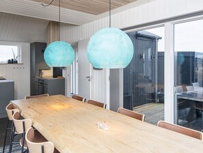 Un comedor moderno con una larga mesa de madera, sillas y dos grandes lámparas colgantes esféricas.