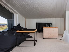 A modern room with a black sectional sofa, a wooden coffee table, a TV, and a dresser. - 5 Star Holiday Home in Harboore (Harboore)