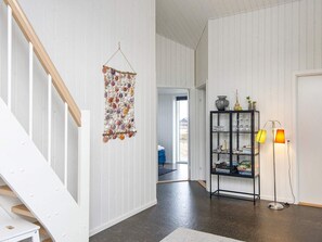 A hallway with a staircase, a wall-mounted decorative item, a glass cabinet with items, and a floor lamp. - 5 Star Holiday Home in Harboore (Harboore)
