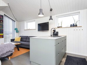A compact living space with a kitchenette, a sofa, a coffee table, and a television mounted on the wall. - 5 Star Holiday Home in Harboore (Harboore)