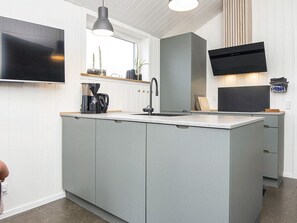 A modern kitchen with a built-in island, a flat-screen TV, and a coffee maker.