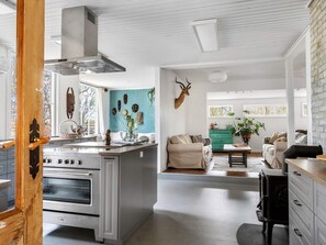 A modern kitchen with a large stove, a dining area with a green cabinet, and a living room with a sofa and a coffee table.