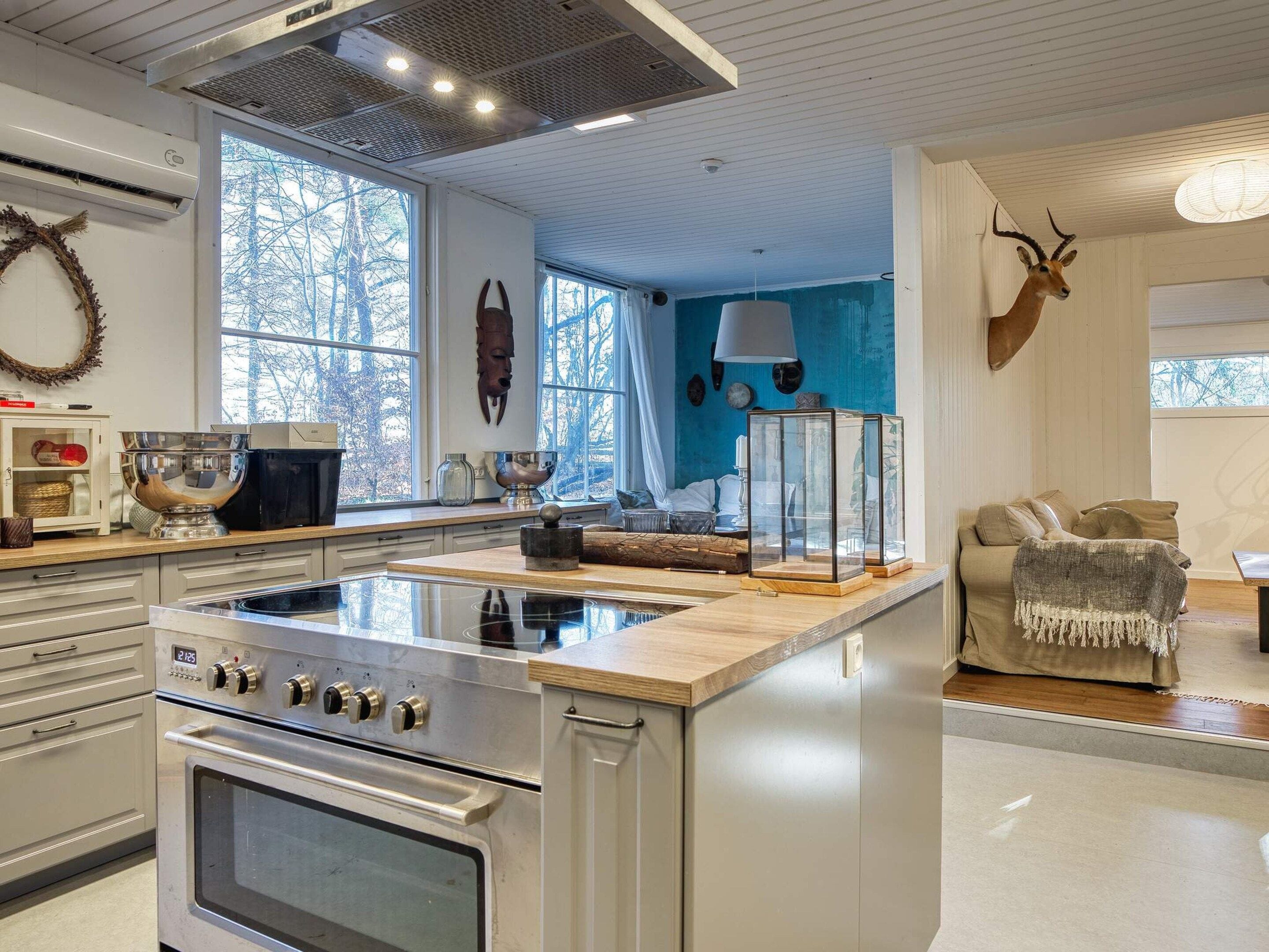 A kitchen with a central island, a stove, and a dining area with a sofa and a decorative antler.