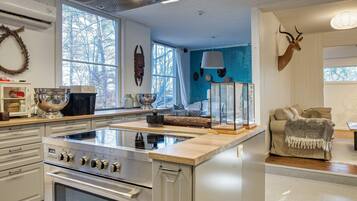 A kitchen with a central island, a stove, and a dining area with a sofa and a decorative antler.