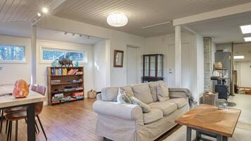 A cozy living room with a sofa, a wooden table, and a bookshelf.