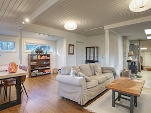 A cozy living room with a sofa, a wooden table, and a bookshelf.