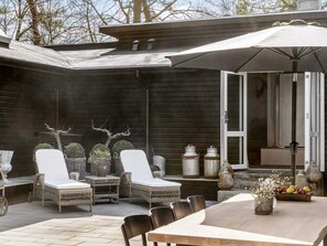 A patio with wicker furniture, a table, and a large umbrella.