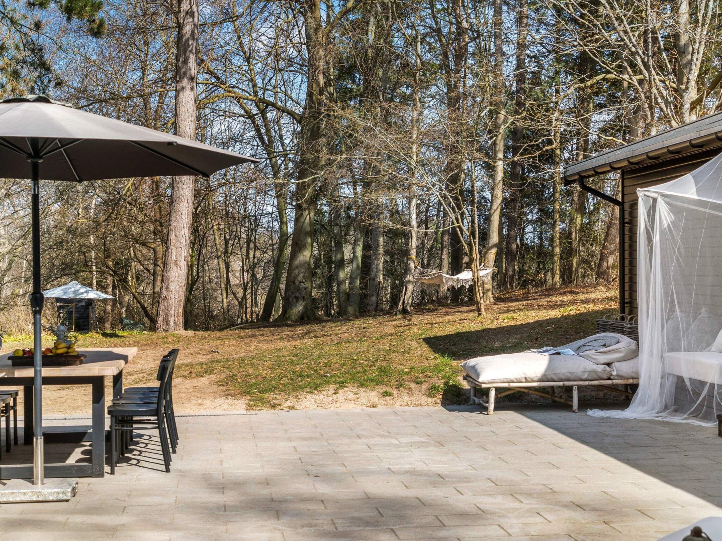 A patio area with a table and chairs, a hammock, and a bed with a canopy.