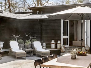 A patio with wicker furniture, a table, and a large umbrella. - 18 Person Holiday Home in Frederiksvaerk (Frederiksvaerk)