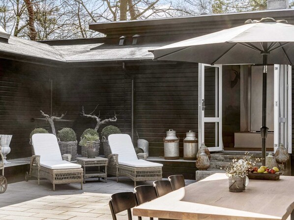 A patio with wicker furniture, a table, and a large umbrella.