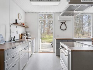 A modern kitchen with a large window, a built-in oven, and a coffee machine.
