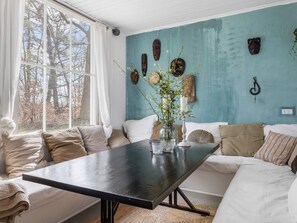 A cozy room with a large window, a dark wooden table, and a blue wall adorned with decorative items.