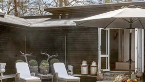 A patio with wicker furniture, a table, and a large umbrella. - 18 Person Holiday Home in Frederiksvaerk (Frederiksvaerk)