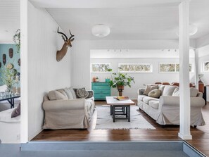 A spacious living room with a wooden floor, two sofas, a coffee table, and a decorative antler.