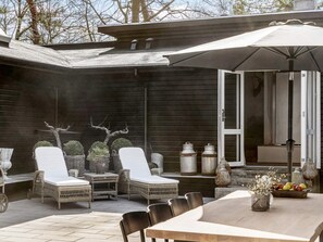 A patio with wicker furniture, a table, and a large umbrella.