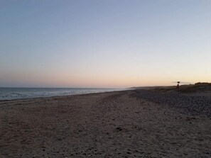 A beach with a signpost, pebbles, and the ocean.