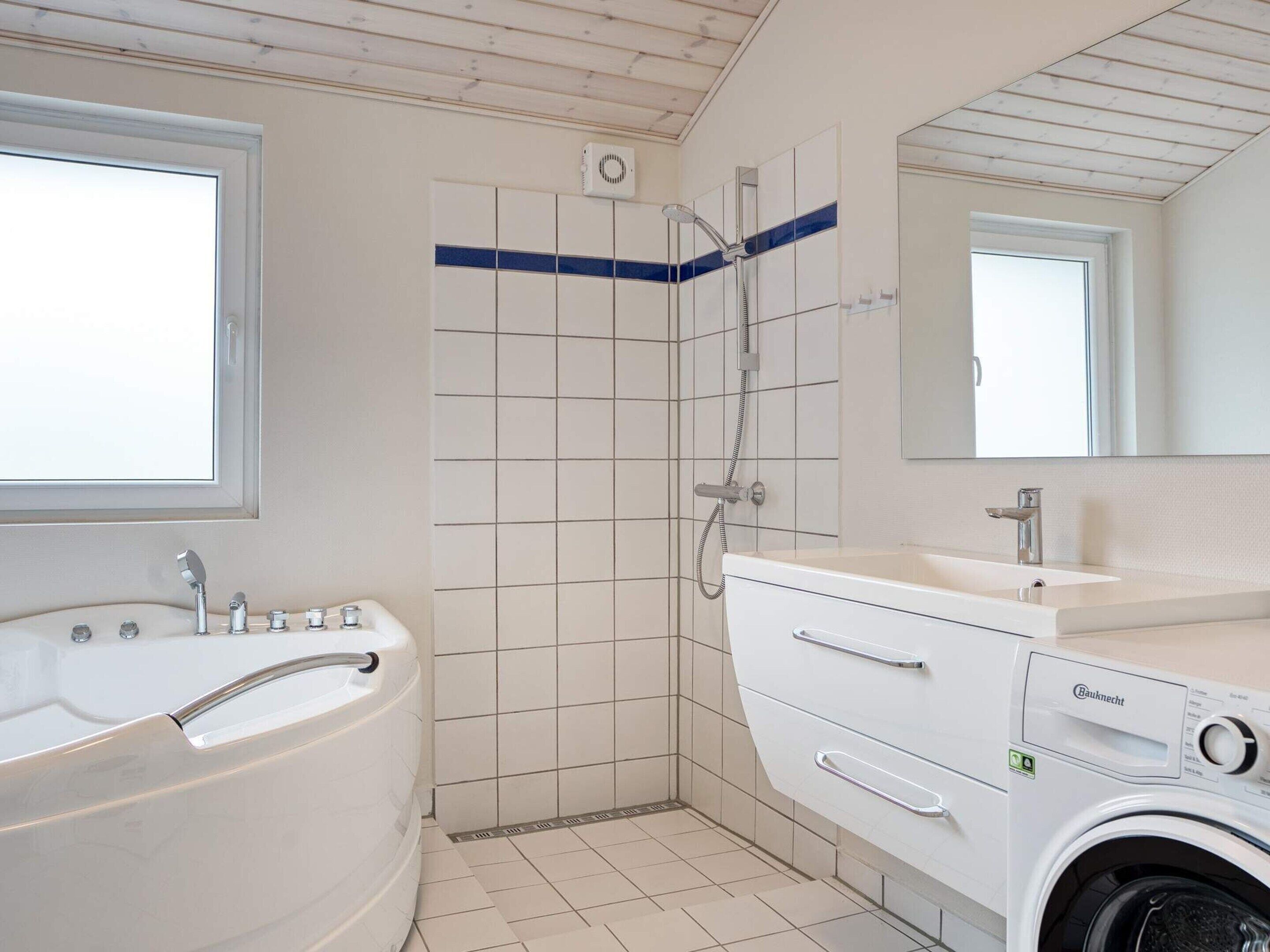 A bathroom with a bathtub, a shower, a sink, and a washing machine.