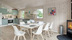A modern kitchen with wooden cabinets, a dining area with a table and chairs, and a fireplace. - 6 Person Holiday Home in Nykobing Sj (Nykobing Sjaelland)