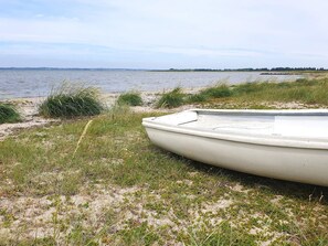 A boat on a sandy shore with water and distant land in the background. - 10 Person Holiday Home in Karby (Øster Assels)