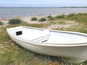 A boat on a grassy shore by a body of water. - 10 Person Holiday Home in Karby (Øster Assels)