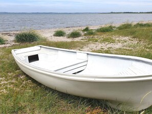 A boat on a grassy shore by a body of water. - 10 Person Holiday Home in Karby (Øster Assels)