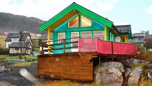 A colorful house with a green roof, a red balcony, and a brick base.