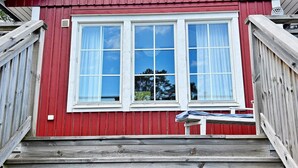 Un edificio de madera roja con un marco blanco en la ventana y un pequeño porche.