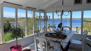 A covered porch with a table and chairs, a potted plant, and a view of a lake.