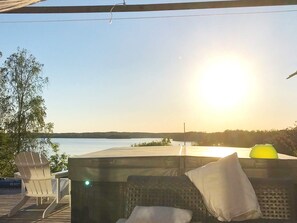 A sunlit outdoor seating area with a view of a lake and distant trees. - 4 Star Holiday Home in Trollhattan (Trollhattan)
