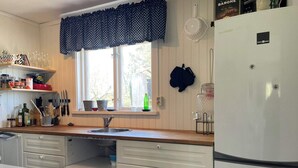 A kitchen with a window, sink, cabinets, and a refrigerator.